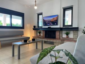 a living room with a tv and a fireplace at Casa Posidonia in Korinthos
