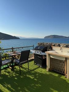 a patio with a grill and a table and chairs at Tholos Alexandra's Beachfront House in Kavoúsion