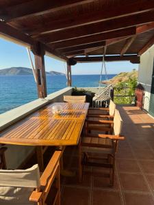 a wooden table and chairs on a deck with the ocean at Tholos Alexandra's Beachfront House in Kavoúsion