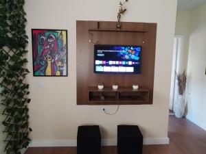 a living room with a flat screen tv on a wall at Casa com 01 qto 42m2 in Poços de Caldas
