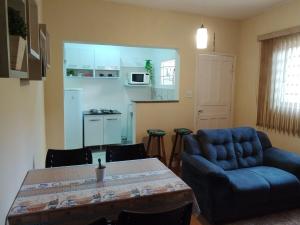 a living room with a blue couch and a table at Casa com 01 qto 42m2 in Poços de Caldas