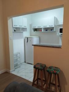 a kitchen with two stools and a white refrigerator at Casa com 01 qto 42m2 in Poços de Caldas +16 photos
