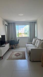 a white bedroom with a bed and a large window at Luxury 3 minutes from the Porto da Barra beach - Fast Wi-Fi, new apartment in Salvador