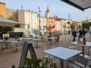 un groupe de tables et de chaises dans une cour avec des bâtiments dans l'établissement Maison de ville authentique au coeur de Leucate, à Leucate