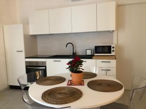 a kitchen with a table with three chairs and a kitchen with white cabinets at Triscele21 in Marina di Ragusa