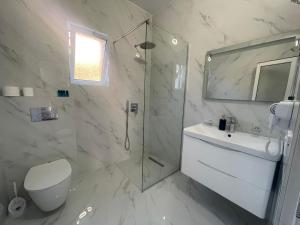 a bathroom with a shower and a toilet and a sink at Vila Makla in Sarandë +47 photos