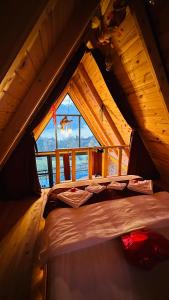 a bed in the attic of a cabin with a window at sitiela bungalov kir evi in Çamlıhemşin