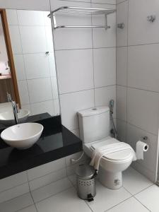 ein weißes Badezimmer mit Toilette und Waschbecken in der Unterkunft Iloa Resort e residence in Barra de São Miguel