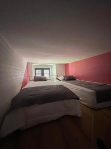 two beds in a bedroom with a pink wall at Barbabianca Apartment in Koper +2 photos