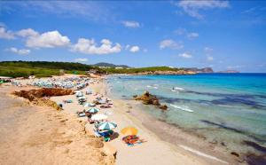 una playa con sombrillas y gente en la playa en Hostal Los Pinos en Es Cana