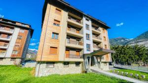 a tall apartment building with mountains in the background at Appartamento Torino 61 - Affitti Brevi Italia in Oulx