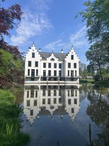 a large white house with its reflection in the water at HEERLIJK CHALET MIDDENIN DE NATUUR! in Putten