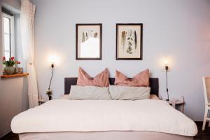 a bedroom with a large white bed with pink pillows at Pension Adele - Ruhig, direkt am Elberadweg & Badesee mit Balkon in Dresden