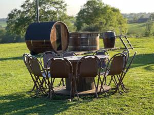 MilwichGreenFeilds Glamping Stargazing Yurts and Outdoor Spa的田野里的一张桌子、几把椅子和一个桶