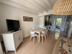 a living room with a table with chairs and a television at Duplex résidence avec piscine sur Anglet in Anglet