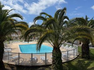 a pool with palm trees and chairs in a resort at Duplex résidence avec piscine sur Anglet in Anglet