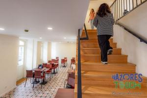 a woman walking down the stairs in a restaurant at Hostel Casa São Pedro - Quarto 2 in Angra do Heroísmo +1 photo