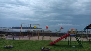 The Pavilion Beach Resort في Jāmb: ملعب مع زحليقة ومرجيح على الشاطئ