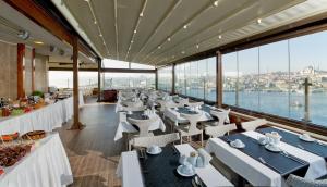 イスタンブールにあるイスタンブール ゴールデン シティ ホテルの白いテーブルと椅子、窓のあるレストラン
