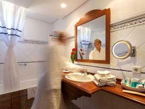 a woman in a bathroom with a sink and a mirror at Hotel Cala Sant Vicenç - Adults Only in Cala de Sant Vicenc