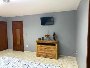 a bedroom with a wooden dresser with a tv on the wall at Casa Jardin Nuñez in Colima