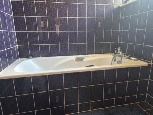 eine Badewanne in einem gefliesten Badezimmer mit Waschbecken in der Unterkunft La Thibaudière - Maison familiale in Montreuil-Bellay