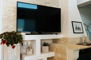 a living room with a tv on a stone wall at Turquoise Front Sea Apartment in Kokkíni Khánion