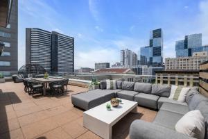 a rooftop patio with a couch and tables on a building at Skyline Suite with Penthouse & Rooftop Deck 6BR by Maddox Hotel in Nashville +46 photos