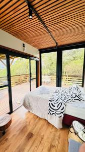 a bedroom with a large bed in a room with windows at TinyFloresta- Pousada Cachoeira da Neve in Urubici +13 photos