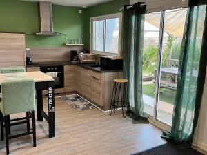 a kitchen with green walls and a table and a table and chairs at Studio ambiance ZEN in Riantec
