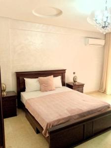 1 Schlafzimmer mit einem Bett, 2 Tischen und einem Kronleuchter in der Unterkunft Appartement en plein centre in Marrakesch + 10 Fotos