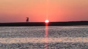 een zonsondergang over het water met een toren in de verte bij Chalet Paraiso Compartido in Tulate