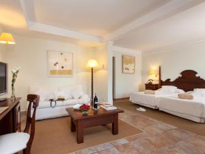 a hotel room with two beds and a living room at Hotel Cala Sant Vicenç - Adults Only in Cala de Sant Vicenc