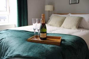 a bottle of champagne and two glasses on a bed at Trendy Apartment in Tralee in Tralee