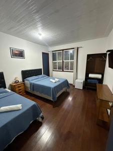 a bedroom with two beds and a table and a desk at Pousada Solar das Gerais in Ouro Preto