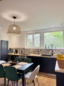eine Küche mit einem schwarzen Tisch und Stühlen und Fenstern in der Unterkunft Villa Cornelia Bagnoles Mezzanine Confort & Nature in Bagnoles de l'Orne