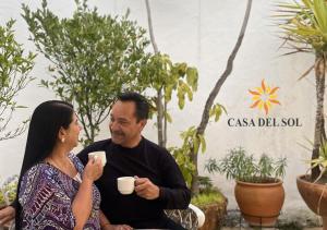 un uomo e una donna seduti su una sedia che tengono in mano delle tazze di caffè di Hotel Casa del Sol a San Cristóbal de Las Casas