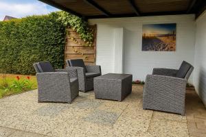 four wicker chairs and a table on a patio at Escape Playero in Breskens
