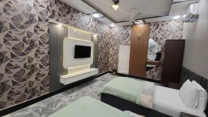 a room with two beds and a tv on a wall at The Lodge Inn in Karachi