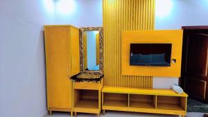 a yellow entertainment center with a tv and a mirror at The Lodge Inn in Karachi