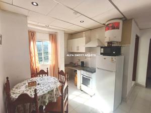 a kitchen with a table and a white refrigerator at ALFA SWEET APARTS in Formosa