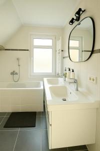 a white bathroom with a sink and a mirror at Escape Playero in Breskens +27 photos