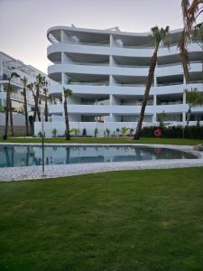 a large white building with a swimming pool in front of it at Portomare Holidays in Motril