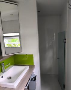 a bathroom with a white sink and a mirror at MH 462 Les dunes de Contis 2 chambres et 2 salles de bains dans camping 4 étoiles in Saint-Julien-en-Born +11 photos
