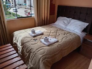 a bed with two towels and two cups on it at La Terraza de Huaruro in Cabanaconde