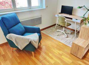 a living room with a blue chair and a desk with a computer at Grand F1 sécurisé hypercentre calme 3mins de la gare in Thionville +22 photos