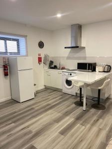 a white kitchen with a table and a white refrigerator at Casa PEREIRA 4 in Ponta do Pargo