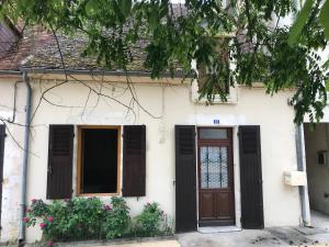 a white house with brown doors and flowers at les petits sportifs in Léré