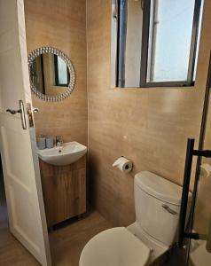 a bathroom with a toilet and a sink and a mirror at Nkandela Village in Lusaka +4 photos