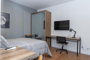 Un dormitorio con una cama y un escritorio con televisión. en Guaja 745 - Apartamento Kiko, en Belo Horizonte